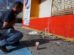 Un hombre reza a las afueras de una tienda donde hombres armados abrieron fuego contra personas que, finalmente, fallecieron. AFP / H. Martínez