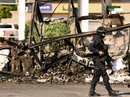 Un policía pasa junto a un vehículo quemado en octubre de 2019, en el llamado “Culiacanazo”. Hoy enfrentan otra crisis en el Estado. AFP