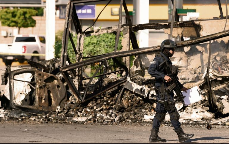Un policía pasa junto a un vehículo quemado en octubre de 2019, en el llamado “Culiacanazo”. Hoy enfrentan otra crisis en el Estado. AFP